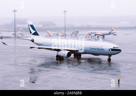 DEC 6, 2018 Narita, Japon - avion de la compagnie aérienne Cathay Pacitfic la pluie pendant le mauvais temps à l'aéroport international Narita de Tokyo avec le personnel au sol wor Banque D'Images