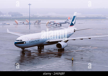 DEC 6, 2018 Narita, Japon - avion de la compagnie aérienne Cathay Pacitfic la pluie pendant le mauvais temps à l'aéroport international Narita de Tokyo avec le personnel au sol wor Banque D'Images