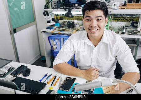 Happy Young Asian man apprécie de travailler à l'atelier de réparation smartphone Banque D'Images