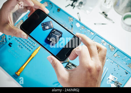 Mains de man photographing démonté smartwatch après l'installation de batterie Banque D'Images