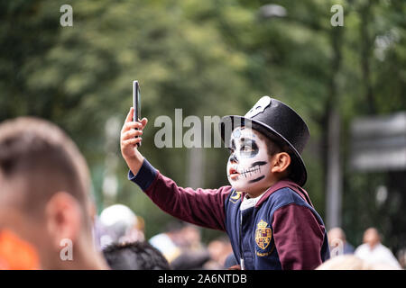 La ville de Mexico, Mexique. 26Th Oct, 2019. Un petit garçon dans la fantaisie robe prend une pendant la Catrina selfies Festival. Des milliers de personnes sont descendues dans les rues de Mexico pour regarder la procession de Catrinas. Catrina est un squelette féminin avec un grand chapeau, souvent faite de plumes. Le chiffre est basé sur un personnage créé au début des années 1900 par l'artiste José Guadalupe Posada et ensuite réinventé par Diego Rivera. Credit : SOPA/Alamy Images Limited Live News Banque D'Images