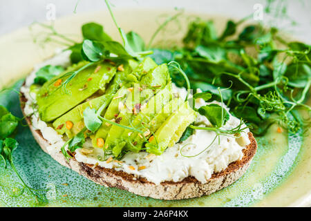 Toast de pain de seigle avec du fromage à la crème et de l'avocat sur un beau plat. Petit-déjeuner sain concept. Banque D'Images