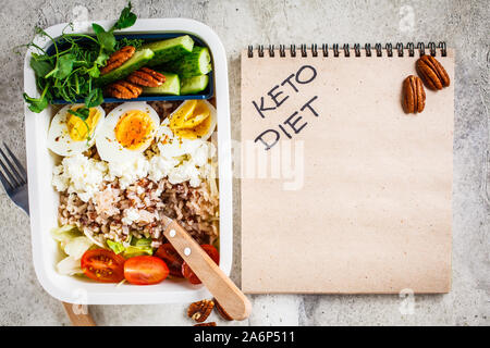 Boîte à lunch avec keto alimentation nourriture, vue du dessus. Riz au poisson, fromage, oeufs et légumes dans des contenants alimentaires. Banque D'Images