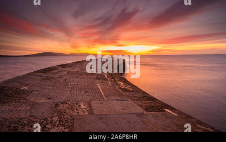 Lyme Regis, dans le Dorset, UK. 28 Oct, 2019. Météo France : beau lever de soleil à la Cobb, Lyme Regis. Le ciel au-dessus de l'historique mur de Cobb brille avec éclat de couleur sur un froid matin d'automne. Credit : Celia McMahon/Alamy Live News Banque D'Images