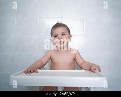 1 ans bébé est assis sur une chaise haute en attente de son repas Banque D'Images