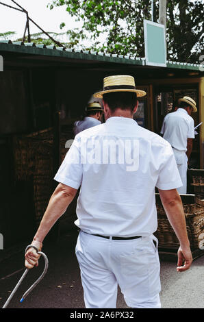 Monte, Madeira, Portugal - Sep 14, 2019 : panier en osier traîneaux pilote, Carreiros do Monte. Moyen de transport traditionnel entre Funchal et Monte maintenant, attraction pour les touristes. Chapeau de paille typique. Banque D'Images