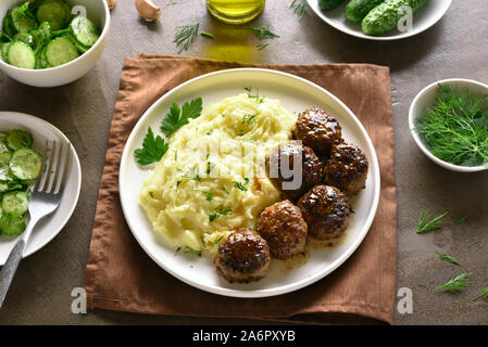 Close up d'escalopes de viande hachée avec de la purée de pommes de terre sur la plaque blanche sur fond brun. Banque D'Images