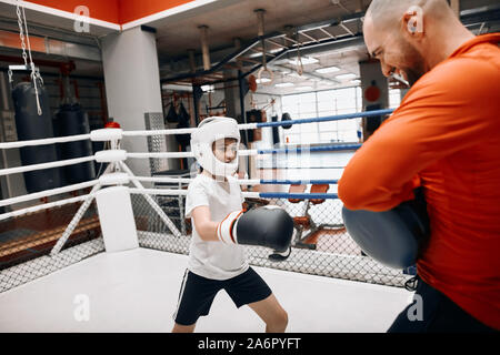 Petit garçon va dans le sport. compat pour légitime défense, remise en forme, la photo en gros.kid frappant avec son entraîneur Banque D'Images