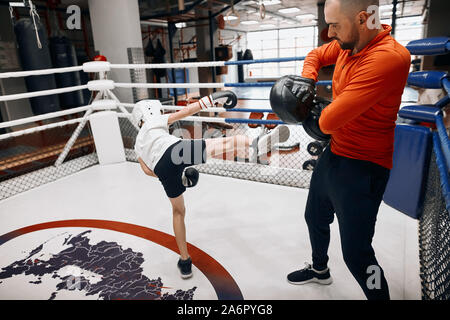 Young boy performing poinçons, pleine longueur latérale sur la photo.L'apprentissage des techniques de coups de pied pour enfants Banque D'Images