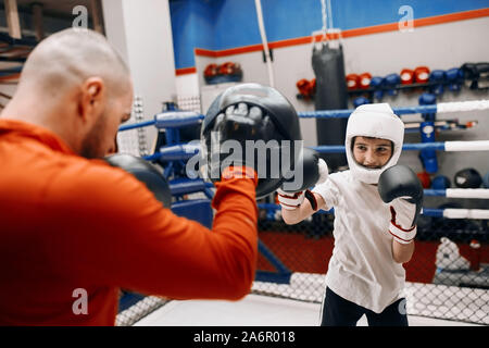 Jeune garçon faisant le kickboxing avec sportif musculaire en orange sport. close up photo recadrée Banque D'Images