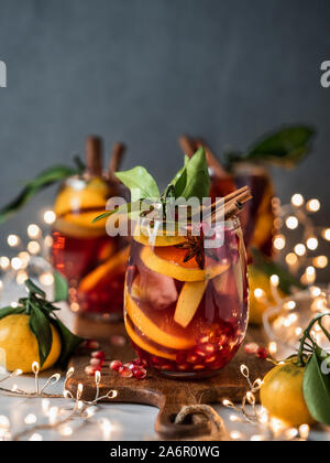 Sangria d'hiver sombre sur fond de vacances de Noël. Jugful avec verres de sangria et tranche de fruits, la grenade et d'épices. L'espace pour copier du texte ou dessin. La verticale. Banque D'Images