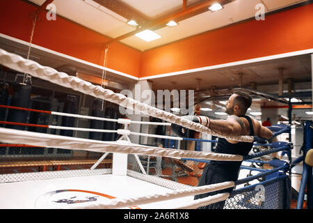 Ambiance assez épuisé boxer couché sur les cordes du ring. close up sside vieww. photo copie espace , détente concept Banque D'Images