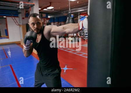 Jeune homme bien bâti qui fréquentent des cours de boxe, la photo en gros. rés.formation. santé et soins du corps, défi Banque D'Images