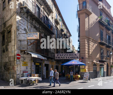 Une scène de rue à Palerme, un homme debout à l'extérieur d'un restaurant Pizzeria, Trattora. Banque D'Images