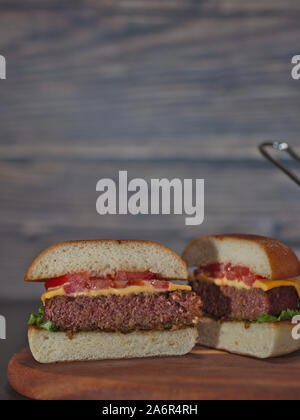 Gros plan vertical sur vegan burger à base de plantes réduit de moitié servis sur plateau en bois Banque D'Images