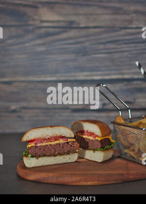 Base de plantes vegan burger réduit de moitié avec des frites servis sur plateau en bois Banque D'Images