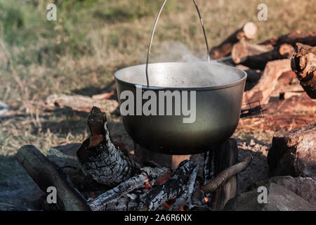 La préparation d'une soupe en noir utilisé s'enflammera le feu ouvert, repas camping Banque D'Images