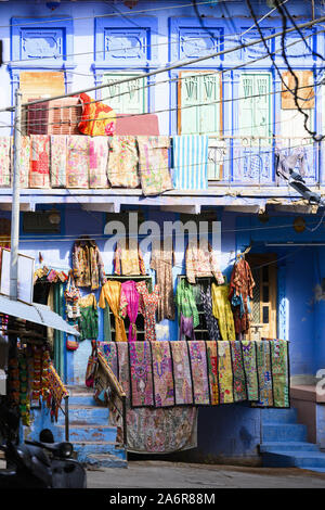 Vue imprenable de vêtements colorés, vestes, sacs et patchwork étendus dehors un petit magasin dans les rues de la ville bleue de Jodhpur. Banque D'Images