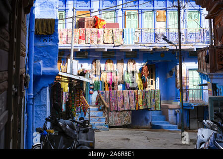 Vue imprenable de vêtements colorés, vestes, sacs et patchwork étendus dehors un petit magasin dans les rues de la ville bleue de Jodhpur. Banque D'Images