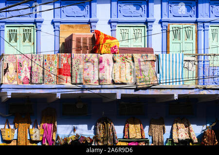 Vue imprenable de vêtements colorés, vestes, sacs et patchwork étendus dehors un petit magasin dans les rues de la ville bleue de Jodhpur. Banque D'Images