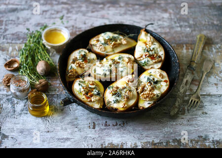 De moitié les poires dans une casserole avec Dorblu au four fromage, miel, noix et le thym. La cuisine française. Régime céto. Focus sélectif. Banque D'Images