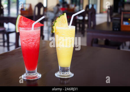 La pastèque et l'ananas fruits tranchés, gros plan secoue pièces, paille, deux fruits avec garniture dans verres transparents sur table dans un bar, boisson froide Banque D'Images