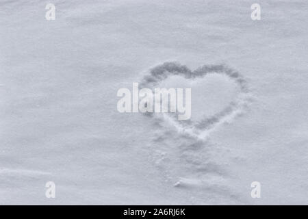 Un coeur dans la neige. Forme de coeur sur la neige vierge douce. Fond d'hiver Banque D'Images