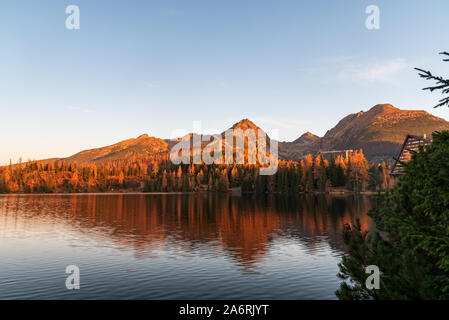 Strbske Pleso lake avec des pointes au-dessus à Vysoke Tatry montagnes en Slovaquie au cours de matin d'automne avec un ciel clair Banque D'Images