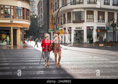 Une femme âgée traverse une route avec une jeune femme à Valence, en Espagne. Banque D'Images