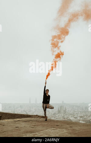 Jeune femme pratiquant le yoga, avec un orange flare dans sa main. Banque D'Images