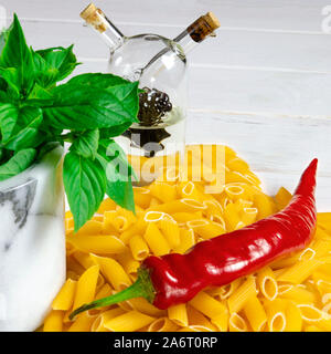 Pâtes penne, vert basilic, parmesan, le sésame, l'Ail, piment, les œufs se trouvent sur un arbre blanc tableau Banque D'Images