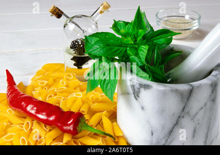 Pâtes penne, vert basilic, parmesan, le sésame, l'Ail, piment, les œufs se trouvent sur un arbre blanc tableau Banque D'Images