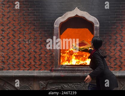 Femme chinoise joss lance les offres de papier à brûler dans le feu de l'Tonghuai temple Guanyue de religion à Quanzhou Banque D'Images