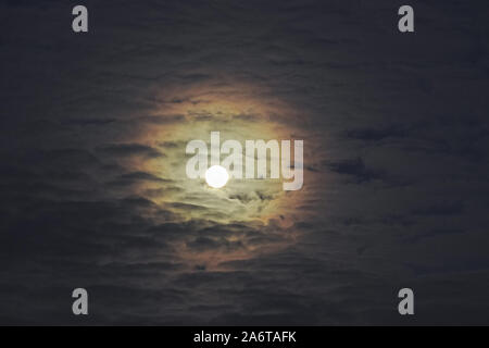 Pleine lune avec altocumulus et coloré à Corona, également appelé aureole (phénomène optique). Banque D'Images