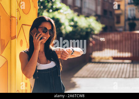 Friendly femme parlant sur l'aimable femme parlant au téléphone et regarder l'heure et regarder l'heure Banque D'Images