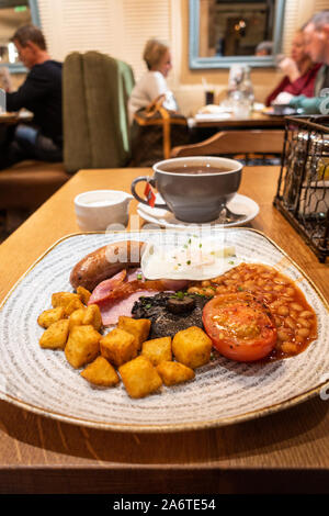 Un petit-déjeuner anglais complet dans un restaurant avec des saucisses, du bacon, des œufs, des haricots blancs, tomates, champignons et pommes de terre frites dans un restaurant. Banque D'Images