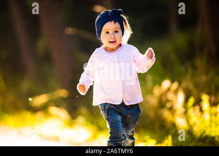 2 ans bébé fille courir en forêt vers la caméra. avec happy expression sur son visage Banque D'Images