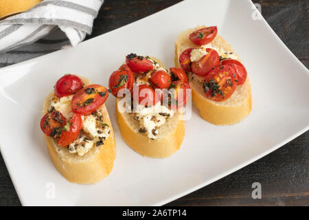 Bruschetta au four garni de tomates raisins, Feta et herbes fraîches : tranches de pain grillé au four garni de fromage feta, tomates raisins, et des herbes fraîches Banque D'Images