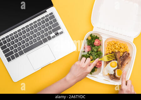 Portrait de femme mangeant de eco emballage avec le maïs, la viande, œufs frits et salade jaune isolé sur Banque D'Images