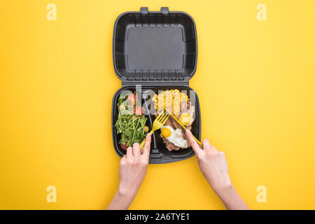 Portrait de femme mangeant de eco emballage avec le maïs, la viande, œufs frits et salade jaune isolé sur Banque D'Images