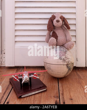 Concept pour les voyages pour les enfants, montrant une peluche sur un globe vintage avec passeport et avion. Banque D'Images