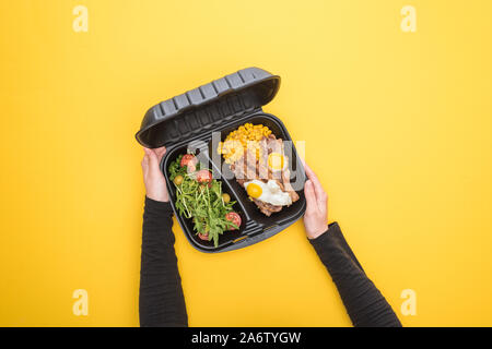 Portrait de femme tenant eco emballage avec le maïs, la viande, œufs frits et salade jaune isolé sur Banque D'Images