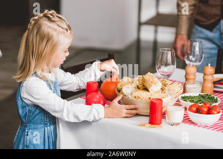 Portrait of cute daughter holding bowl avec le maïs et citrouille à jour de Thanksgiving Banque D'Images