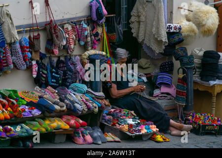 SIGNAGHI, GÉORGIE - Juillet 6, 2019 : Georgian woman sits et vend dans la rue tapis national chaussettes tricotées et Banque D'Images