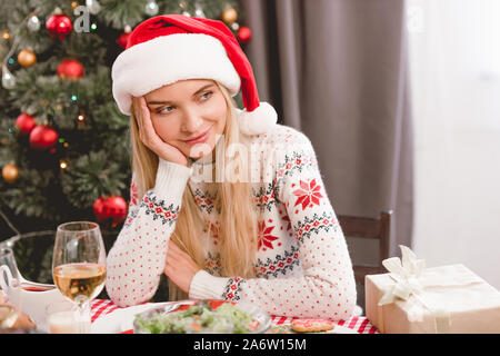 Attractive Woman in santa hat chandail et assis à table à Noël Banque D'Images