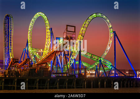 Casino Pier et Hydrus Coucher du Soleil - Soir vue de la colorée et illuminés Casino Pier roue de Ferris et Hydrus roller coaster. Cette image est disp Banque D'Images