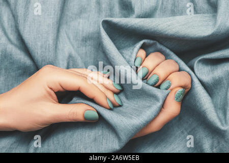 Vue rapprochée de la femme avec les mains manucure mode jeans sur fond de tissu. Vue d'en haut. Banque D'Images