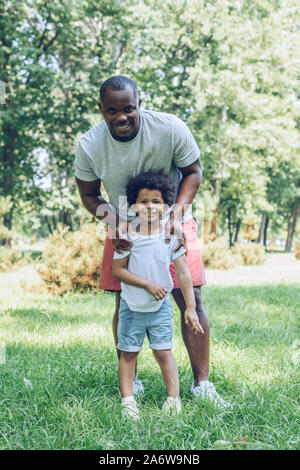 Happy african american father and son smiling at camera while walking in park Banque D'Images