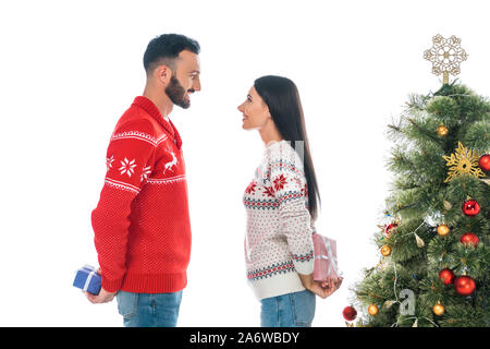 Heureux couple holding gifts near Christmas Tree isolated on white Banque D'Images