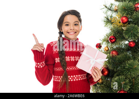 Happy kid holding présent rose et en pointant avec le doigt près de l'arbre de Noël isolated on white Banque D'Images